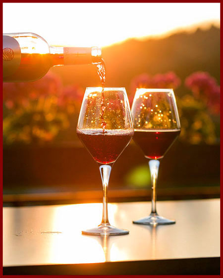 wine being served with a view of a vineyard at sunset in the background