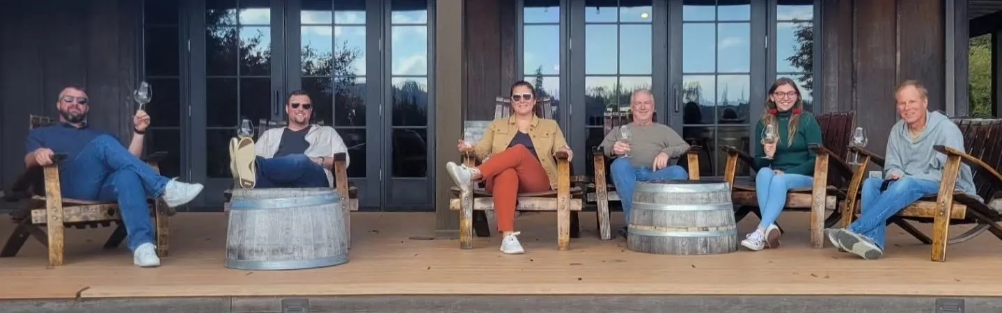 Small group relaxing with wine on a covered patio at a McMinnville winery in Oregon’s Willamette Valley